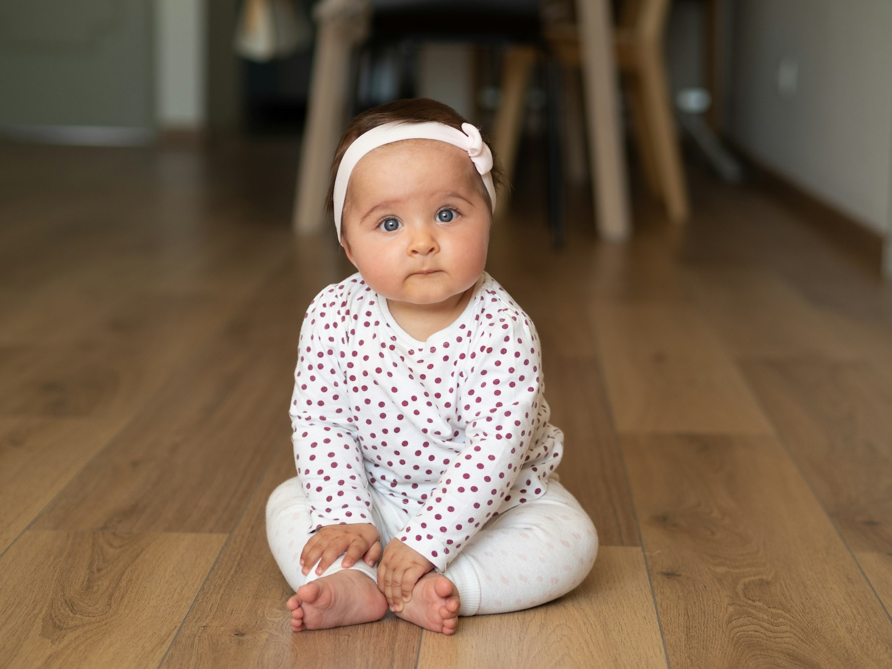 An infant sitting up indoors, alert and curious