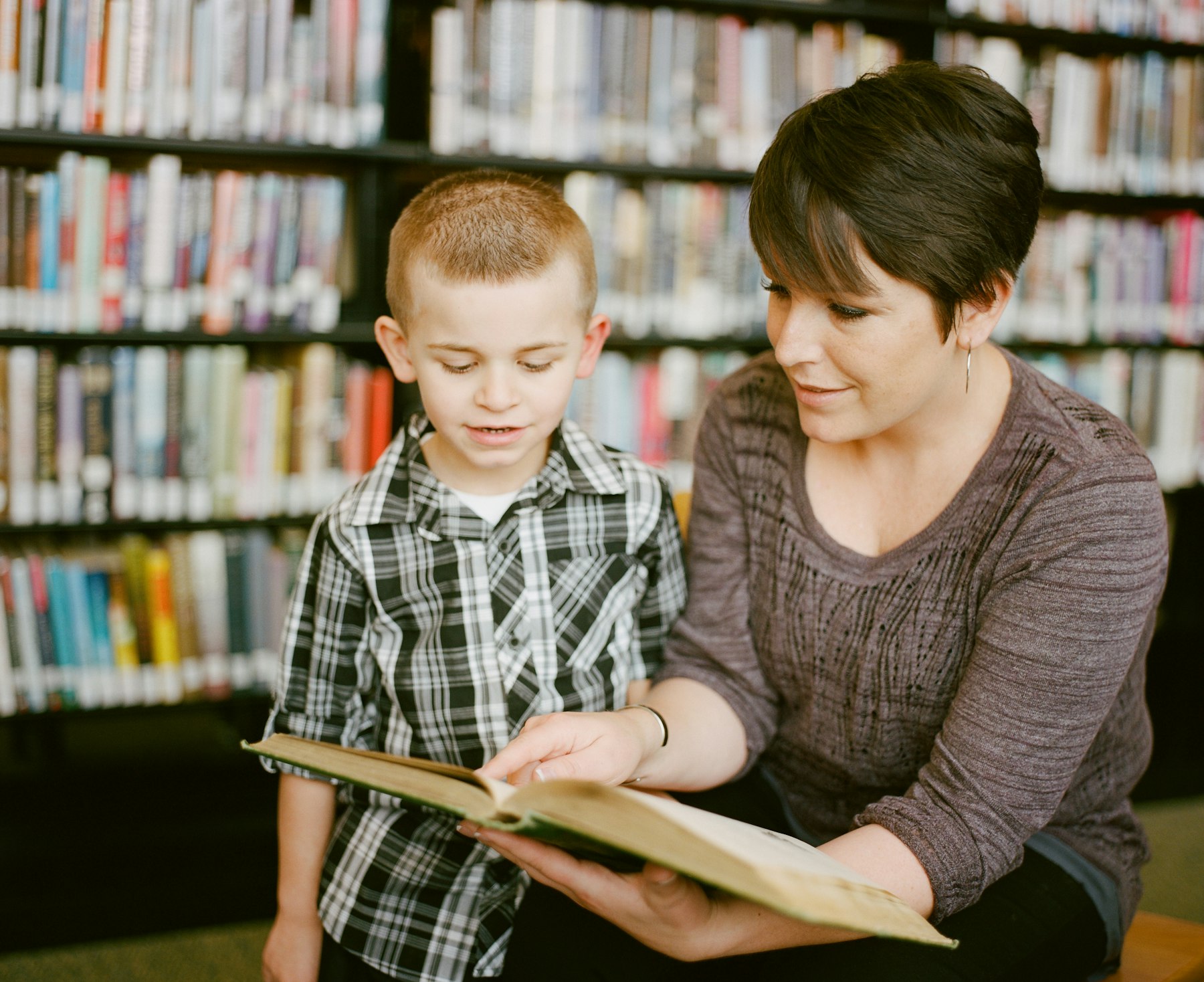 A teacher reading a book together with a young student