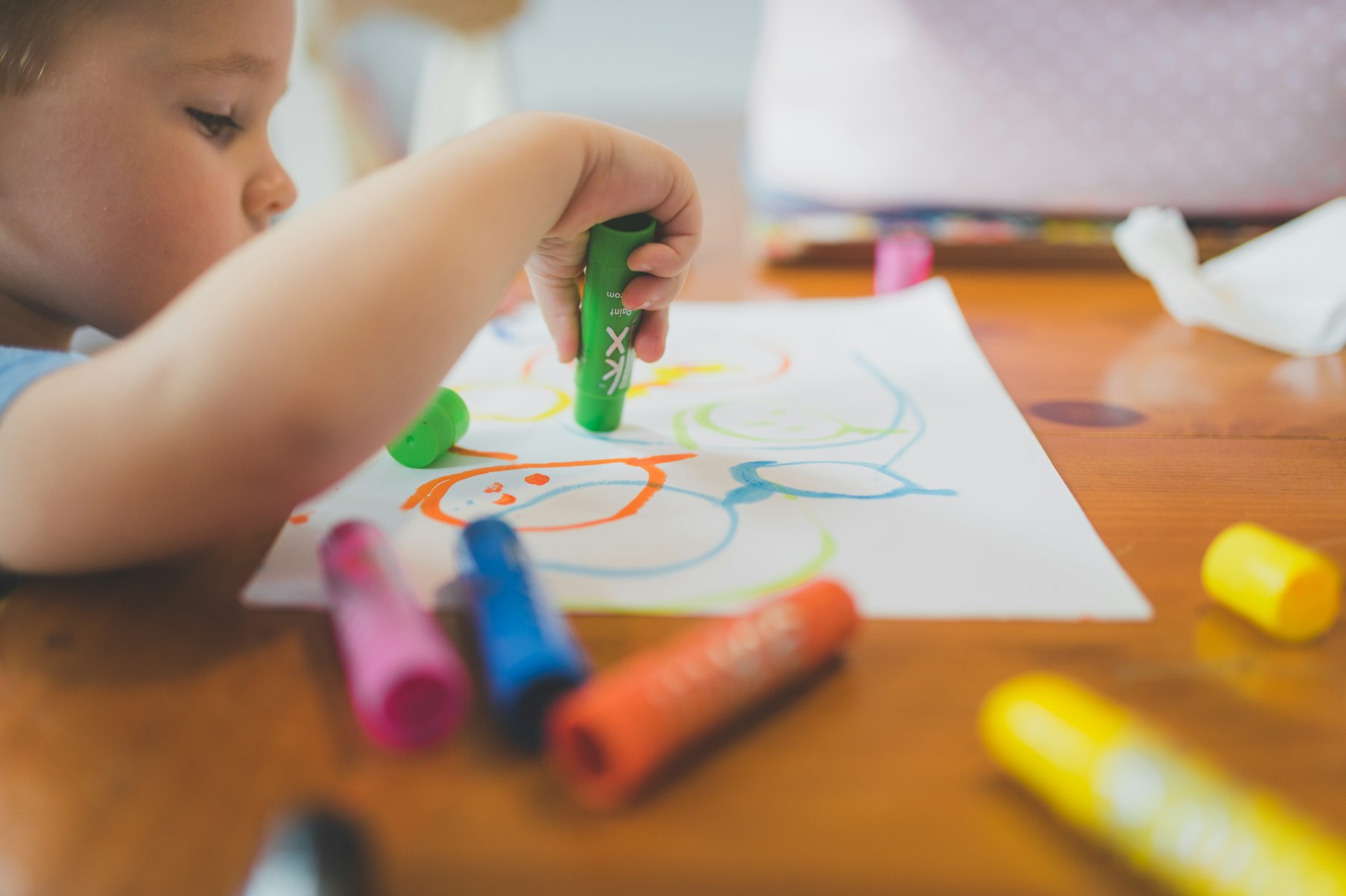 A toddler drawing with markers at a table indoors